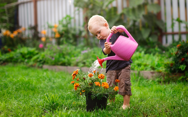 Gartenarbeit im Frühling: kleiner Junge mit Gießkanne