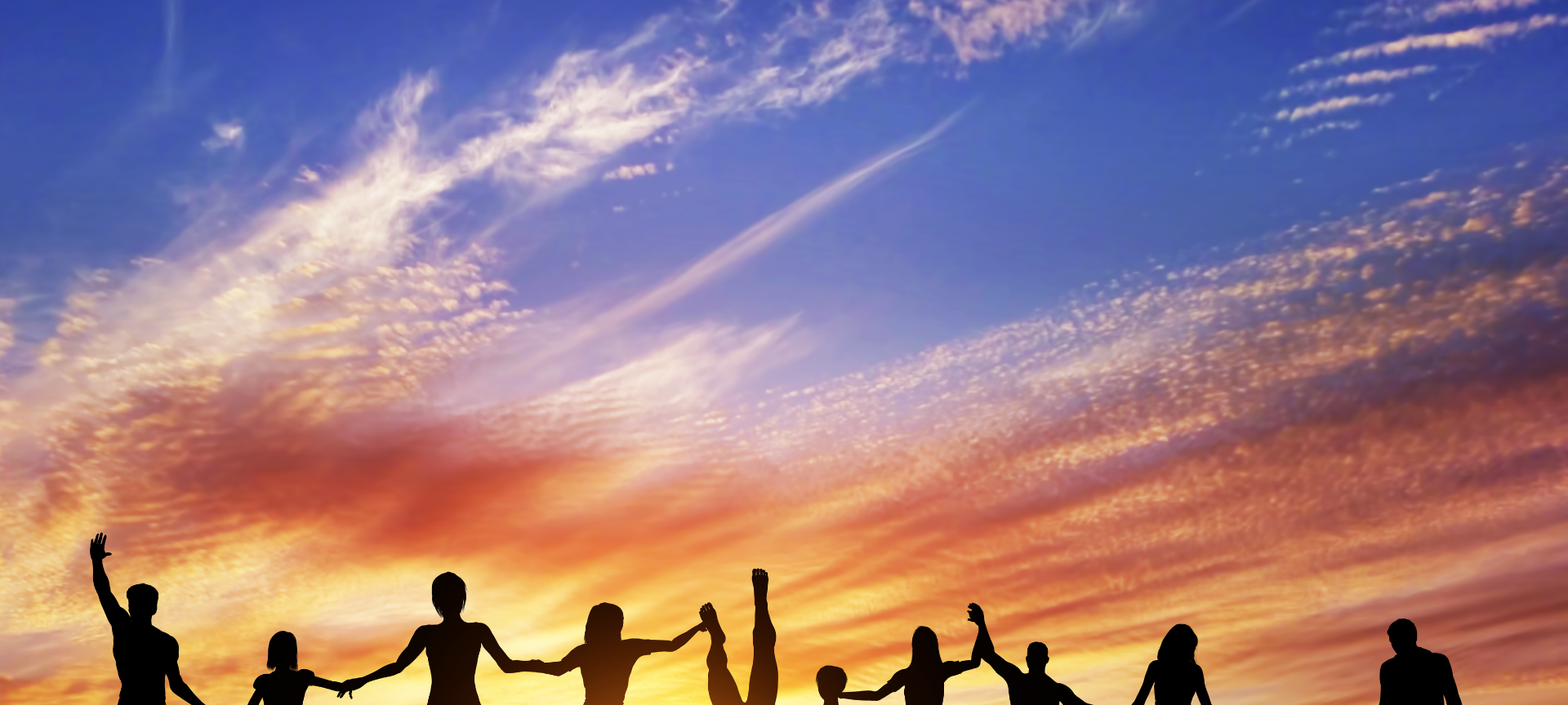 Neujahrsvorsätze / viele Menschen klein und groß stehen Hand in Hand unter freiem Himmel während die Sonne untergeht